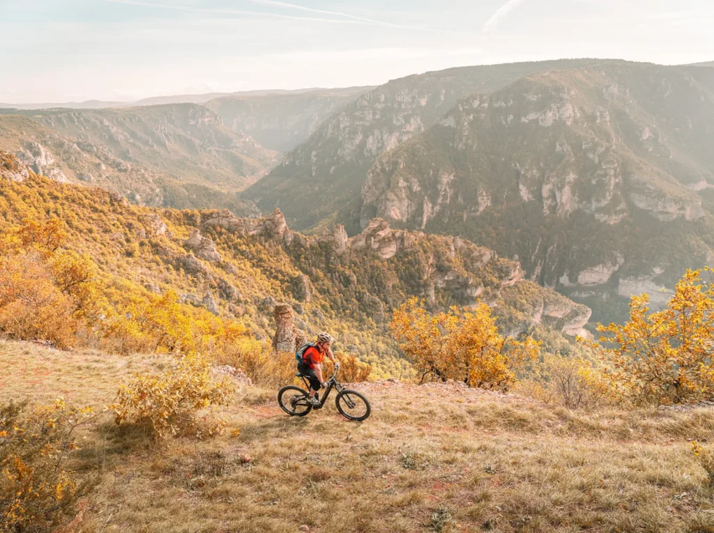 A cyclist mountain biking on the Causse, with a view of the gorges.